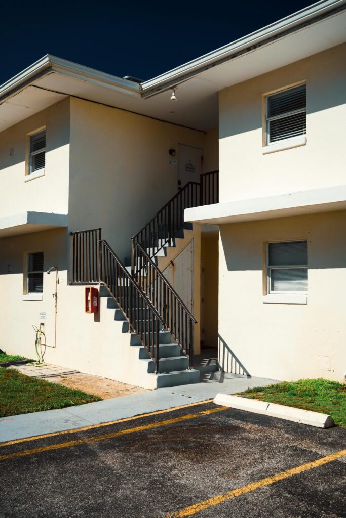 A contemporary apartment building exterior featuring a stairway under bright sunlight.